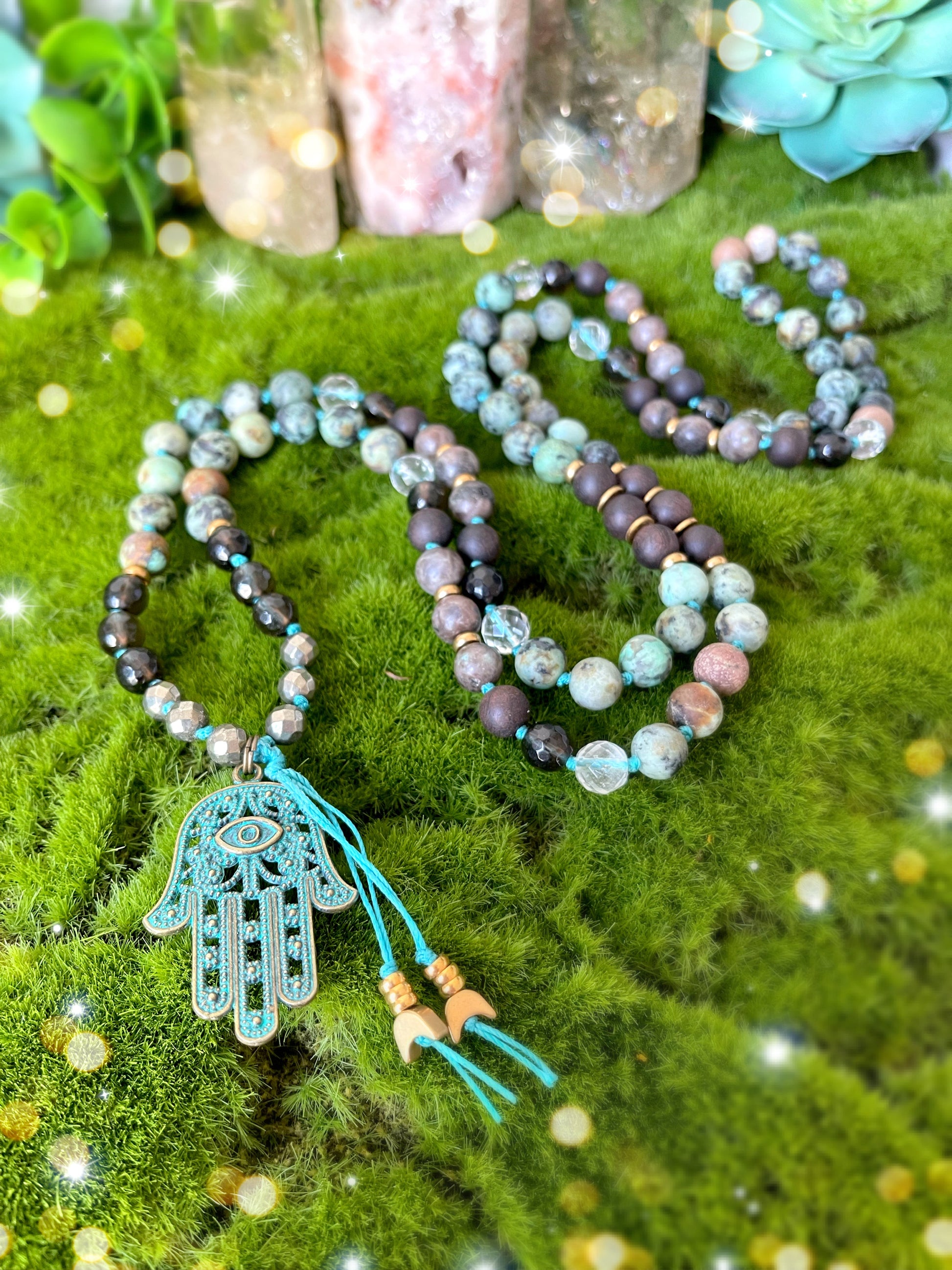 Hand of Fate Mala.  108 beads of Pyrite, Matte African Turquoise, Smokey Quartz, Clear Quartz and Ebony Black wood with brass spacers and a patina hamsa pendant. Available at The Crystalline Moon.